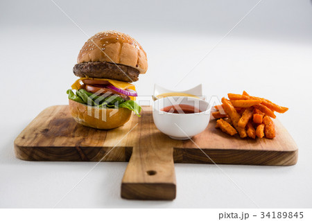 Hamburger by french fries in container on cutting board 34189845