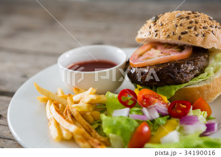 High angle view of hamburger by onion rings with dip and french fries 34190016
