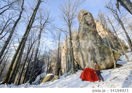 Male hiker nearly his red tent in the mountains 34198925