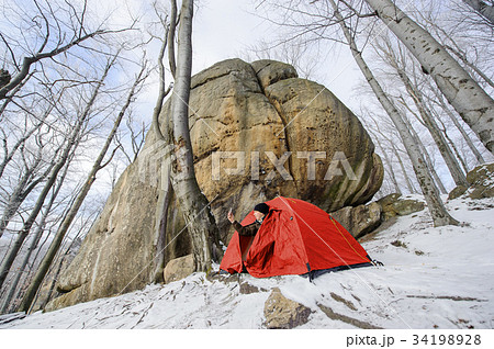 Male hiker nearly his red tent in the mountains 34198928