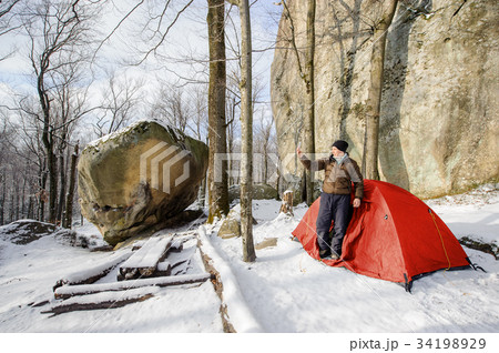 Male hiker nearly his red tent in the mountains 34198929