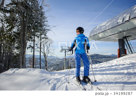 Female skier against ski-lift and winter mountains background Female skier against ski-lift and winter mountains background 34199287