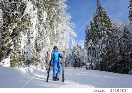 Happy woman skier on a ski slope in the forest Happy woman skier on a ski slope in the forest 34199334