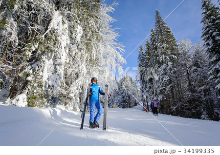 Happy woman skier on a ski slope in the forest Happy woman skier on a ski slope in the forest 34199335