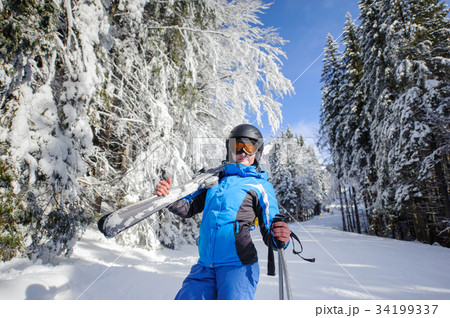 Happy woman skier on a ski slope in the forest Happy woman skier on a ski slope in the forest 34199337