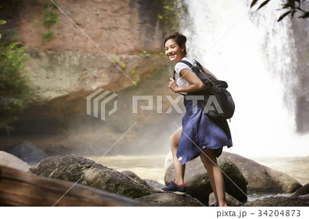 A happy traveler is walking on the rock near the waterfall. A happy traveler is walking on the rock near the waterfall. 34204873