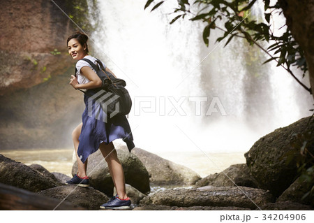 A young traveler is walking on the rock near the waterfall. A young traveler is walking on the rock near the waterfall. 34204906
