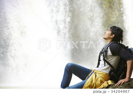 a man is sitting and looking something on the waterfall. a man is sitting and looking something on the waterfall. 34204907