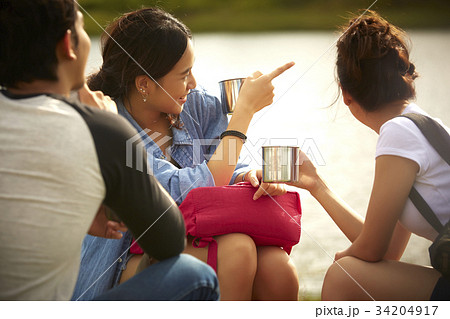 A girl is pointing to something on the river for two friends. 34204917