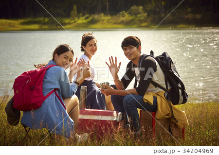three young friends are smiling and looking at the camera by the river 34204969