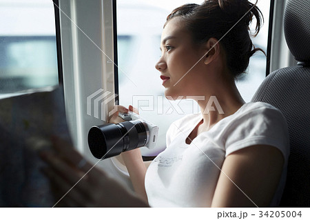 the girl is holding a camera and looking through the train window the girl is holding a camera and looking through the train window 34205004