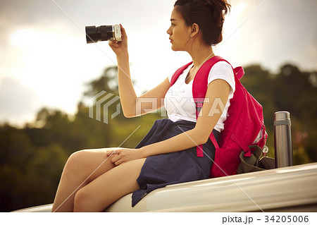 a young girl is sitting and taking photos with her digital camera outdoors a young girl is sitting and taking photos with her digital camera outdoors 34205006