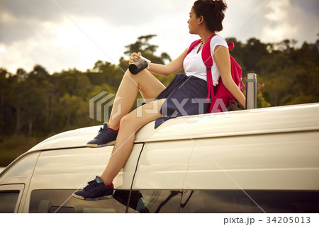 a young girl is sitting on truck's roof and holding a camera a young girl is sitting on truck's roof and holding a camera 34205013