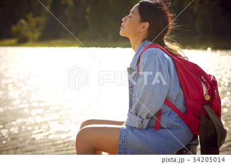 a young girl with backpack is sitting and enjoying fresh air outdoors 34205014