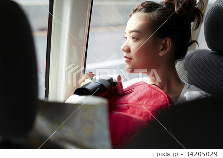 a young girl is holding a backpack and camera inside a truck 34205029
