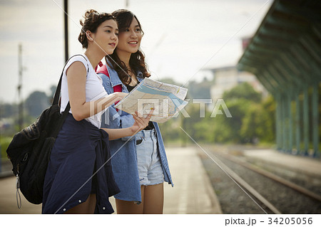 two young travelers are holding map and standing near a railway two young travelers are holding map and standing near a railway 34205056
