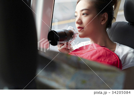 a lovely girl is sitting in a car and holding digital camera 34205084