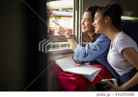 two young asian travelers are watching outside from a train two young asian travelers are watching outside from a train 34205086