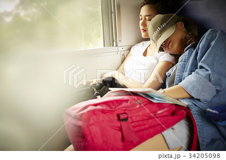 Two young Asian girls are sleeping on a train. 34205098