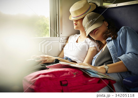 Two Asian girls are leaning on each other's shoulders and sleeping on a train. 34205118