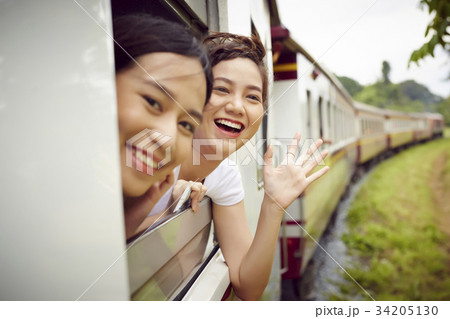 Two young Asian girls are feeling excited when sitting on a train. 34205130