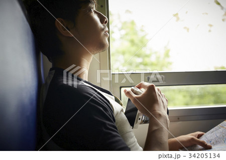 An Asian man is holding a camera and looking at something. 34205134