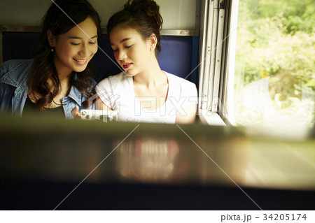Two young girls are looking at the photos they took through the trip. 34205174