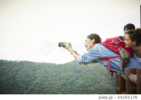 An Asian girl is taking photos of the sightseeing when travelling with friends. 34205176