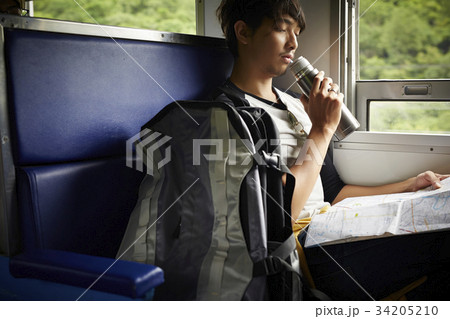 The man is drinking and watching his journey on the map when sitting on a train The man is drinking and watching his journey on the map when sitting on a train 34205210