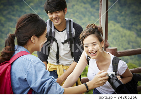 The girl is showing a funny photo in a camera to her boyfriend and girlfriend 34205266