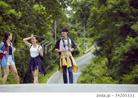 three travellers are walking and chatting together on the road in the jungle 34205331