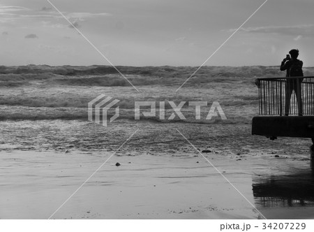 Back view of a tourist taking photo of sea storm 34207229