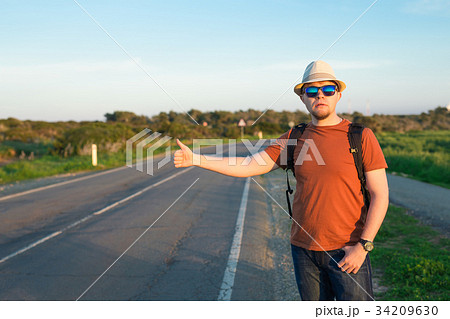 Hitchhiking traveler try to stop car on the 34209630