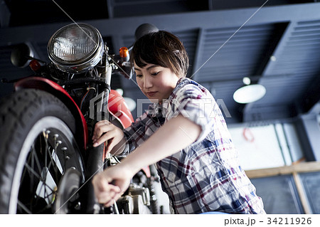 バイクを修理する女性の写真素材