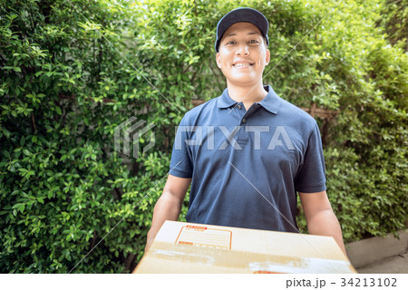 Delivery man smiling while holding a cardboard box 34213102