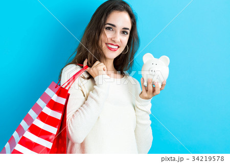 Woman holding piggy bank and shopping bags 34219578