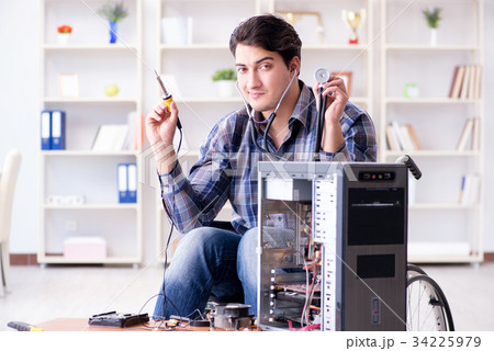 Disabled man on wheelchair repairing computer Disabled man on wheelchair repairing computer 34225979