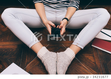 Cropped image of a girl in jeans sits at home Cropped image of a girl in jeans sits at home 34231677
