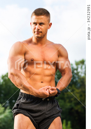 Young bodybuilder flexing muscles outdoors 34232991