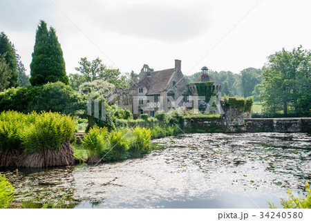 イギリス郊外の歴史的建物と緑に囲まれた池の写真素材