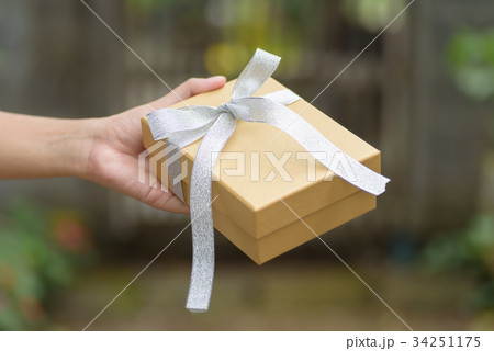 Golden gift box in hand for giving in holidays Golden gift box in hand for giving in holidays 34251175