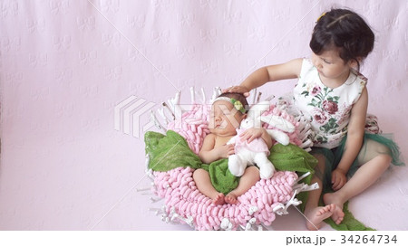 little girl looks at her baby sister little girl looks at her baby sister 34264734