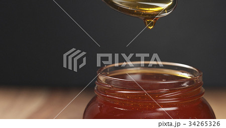 honey pour with spoon in glass jar 34265326