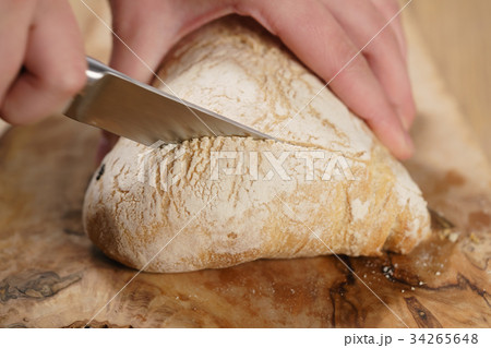 closeup man slicing ciabatta on wood board 34265648