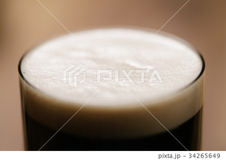 dark beer poured in glass on wood table 34265649