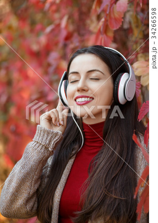 Girl listening music in autumn park Girl listening music in autumn park 34266598
