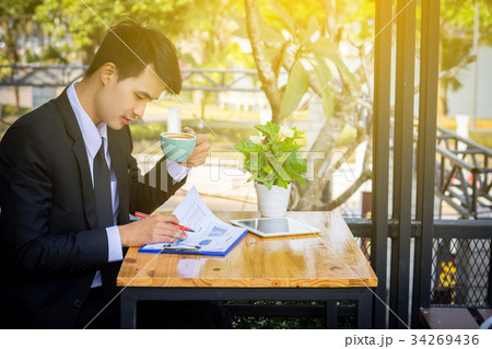 Businessman drinking coffee and reading a report 34269436