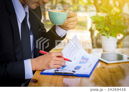 Businessman drinking coffee and reading a report 34269438