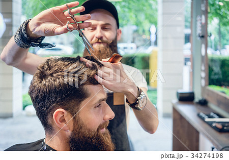 Dedicated hairstylist using scissors and comb 34274198