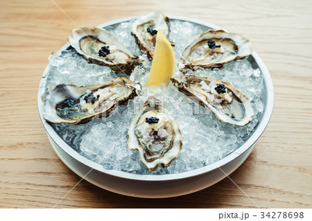 Raw and fresh Oyster with caviar on top and lemon Raw and fresh Oyster with caviar on top and lemon 34278698